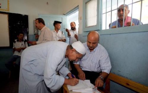 CAIRO - Een Egyptische stemmer wordt geholpen bij het zoeken van zijn naam op een lijst in een school in het Mit Omba district van CaÃ¯ro. Foto EPA.