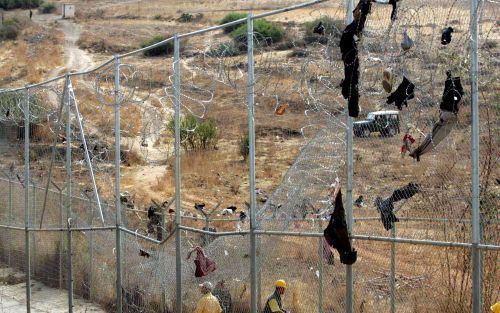 MELILLA â€“ Een achtergelaten pet en handschoen op het hek van de Spaanse enclave Melilla in Marokko. Honder den Afrikanen bestormden donderdag opnieuw de hekken bij de grensovergang om zo de Europese Unie â€˜in te klimmen’. Foto EPA