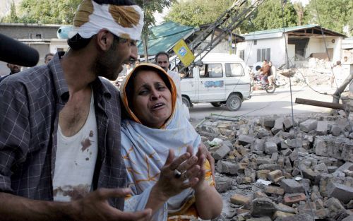 MUZAFFARABAD - Een jongen uit Kashmir troost zondag zijn moeder die rouwt over het verlies van haar dochter. Foto EPA