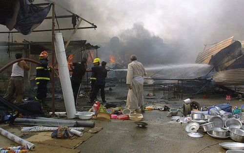 BAGDAD â€“ Brandweerlieden aan het werk na een autobomaanslag op een markt in de Iraakse hoofdstad Bagdad. In de aanloop naar het grondwetsreferendum van zaterdag neemt het aantal aanslagen sterk toe. Foto EPA