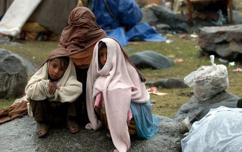 BALAKOT â€“ Een Pakistaanse moeder zit met twee van haar kinderen in een opvangkamp in Balakot. Als bescherming tegen de regen hebben ze niet meer dan een doek. Foto Kjeld Duits