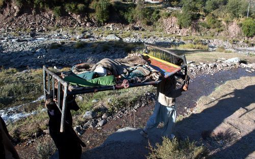 GHNOL â€“ Dorpelingen dragen een gewonde vanuit het bijna volledig geÃ¯soleerde dorpje Ghnol in noordelijk Pakistan naar een opvangkamp. Honderdduizenden slachtoffers van de aardbeving van 8 oktober zijn nauwelijks bereikbaar voor hulpverleners. Foto Kjel