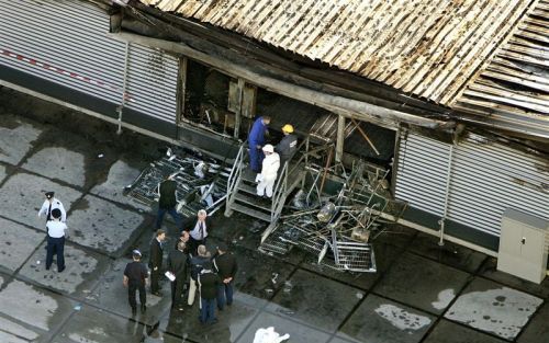 SCHIPHOL - Luchtfoto van het uitgebrande cellencomplex op Schiphol, donderdagmiddag na de brand die het leven eiste van 11 gedetineerden. Onderzoekers, waaronder leden van de marechaussee en de politie, staan voor een verwoest deel van het complex. - Foto