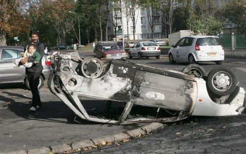 PARIJS â€“ Een inwoner van de Parijse buitenwijk Aulnay sous Bois loopt langs een uitgebrande auto. Ook de afgelopen nacht was het weer onrustig in diverse voorsteden van Parijs. Relschop pers staken zo’n 400 auto’s in brand en beschoten de politie.- Foto