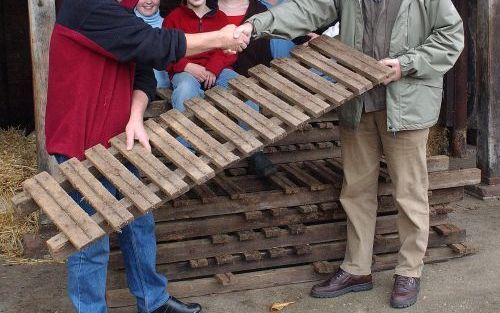 RENSWOUDE â€“ Veenendaler C. Cramer (rechts) neemt een stapel oude vlonderplanken uit een loopgraaf van de Grebbelinie in ontvangst. De vlonders, een unieke vondst, lagen jarenlang in de boerderij van boer J. M. van Ravenhorst uit Renswoude. Foto Piebe Ba