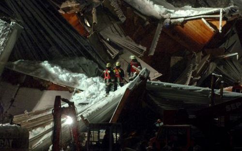 BAD REICHENHALL â€“ Reddingswerkers doorzoeken de puinhopen van een ingestorte ijshal in het Duitse Bad Reichenhall. Het dak van het complex bezweek gistermiddag. Zeker tien mensen kwamen daarbij om het leven. Foto EPA