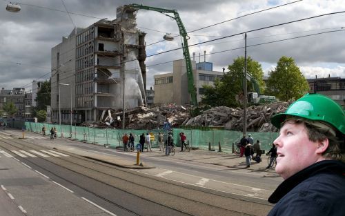 AMSTERDAM â€“ Een sloopkraan van de Beelen Groep uit Nunspeet met een bereik van 44 meter aan het werk in Amsterdam. Inzet: eigenaar Wim Beelen. Fotomontage RD