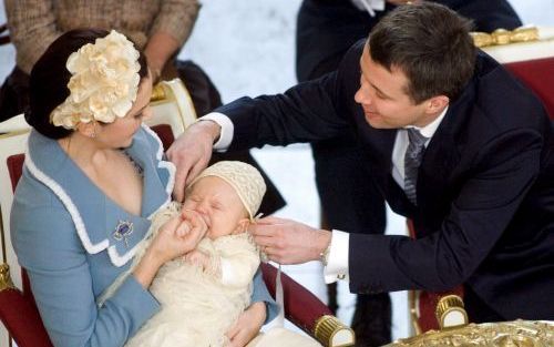 KOPENHAGEN â€“ Kroonprins Frederik van Denemarken zet het mutsje van zijn zoontje Christian recht. Zaterdag werd de eerstgeborene van Frederik en zijn vrouw Mary gedoopt. Foto EPA