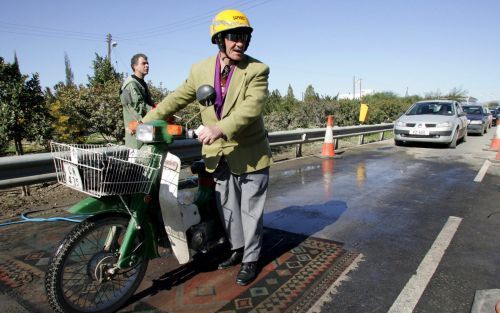 NICOSIA â€“ Een Turks Cypriotische brommerrijder loopt bij een controlepost in Nicosia, Cyprus, over een met desinfectiemiddel bespoten kleed. Na de bevestiging afgelopen zondag van een vogelgriepgeval op het Turkse deel van het eiland besloot de Grieks C