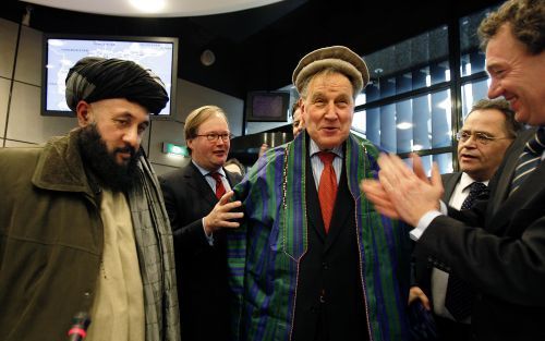 &#61559;DEN HAAG â€“ Het Afghaanse parlementslid Khaleeq (links) overhandigt voorzitter De Haan van de vaste Kamercommissie van Buitenlandse Zaken na afloop van de hoorzitting over de NAVO plannen voor Afghanistan traditionele kledij. De kamerleden Van Ba