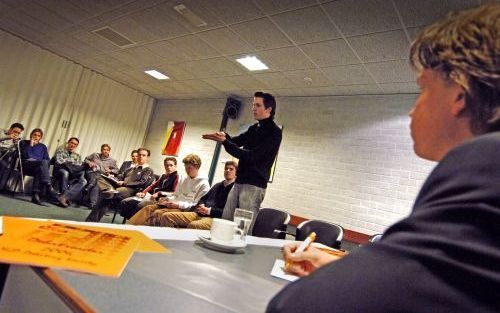 De 'premier'toont tijdens het debat van de SGP Debating Society met zijn handen het harmonika-effect van hard rijden op de snelweg. Trainer Ronald van Bruchem (r.) luistert toe. Foto Erik Kottier