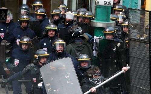 PARIjs - Politieagenten rennen achter een man die een stuk pijp naar de politiebarricade voor de Sorbonne Universiteit in Parijs probeert te gooien. Dinsdag kwam het opnieuw tot rellen tegen het banenplan van premier De Villepin. Foto EPA.