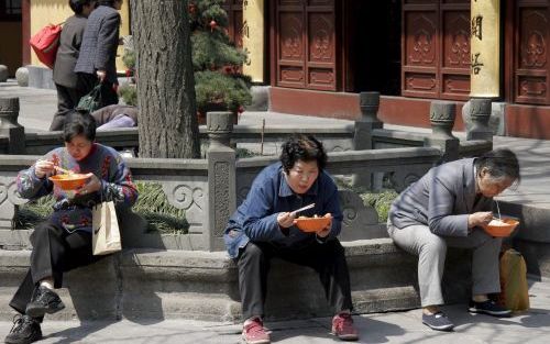 SJANGHAI â€“ Chinezen verorberen noedels in een tempel in Sjanghai. Jaarlijks worden in heel China 45 miljard paar eetstokjes eenmalig gebruikt en weggegooid. Foto EPA