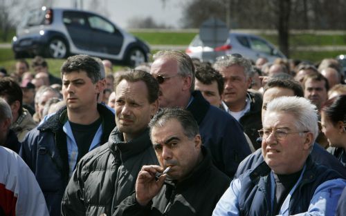 BORN - Werknemers van autofabrikant NedCar luisteren naar toespraken tijdens een protestbijeenkomst over de toekomst van de autofabriek in het Limburgse Born maandagmiddag. Op de achtergrond auto's die in de fabriek gebouwd worden, de Smart en de Mitsubis