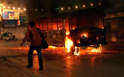 KARACHI - Een Pakistaanse fotograaf loopt langs een brandende bus in Karachi. Een woedende menigte stak dinsdagavond auto's en bussen in brand nadat eerder dinsdag een bomaanslag plaatsvond tijdens een religieuze bijeenkomst. Foto EPA