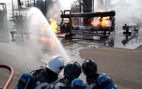 ROTTERDAM â€“ Brandweerlieden bestrijden een vuurhaard. Brandweer, politie en ambulancediensten hielden woensdag op de Maasvlakte en in Hoek van Holland een grootschalige landelijke oefening, waarbij een â€“fictieveâ€“ olie installatie explodeerde. Daarbi