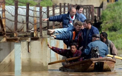 Servische mannen proberen per boot hun huis te bereiken. Honderden huizen in ServiÃ« en Bulgarije zijn vrijdag onder water komen te staan doordat de Donau buiten zijn oevers is getreden. Foto EPA