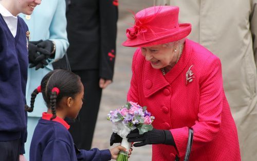 WINDSOR â€“ De jarige Britse koningin Elizabeth II neemt bloemen in ontvangst tijdens een wandeling door het stadje Windsor. Foto EPA