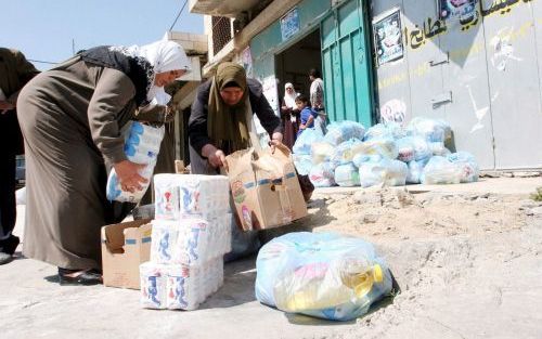 JENIN â€“ Palestijnse vrouwen nemen voedselpakketten in ontvangst in de stad Jenin op de Westelijke Jordaanoever. Doordat veel landen de geldkraan hebben dichtgedraaid, kampen de Palestijnen met ernstige voedseltekorten. Inmiddels is donderdag overeenstem