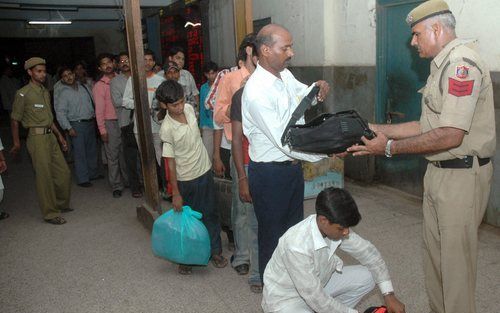 NEW DELHi - Een Indiaanse politieman doorzoekt de bagage van een passagier op het treinstation van New Delhi. In heel India zijn de veiligheidsmaatregelen verscherpt na de serie bomexplosies in Mumbai. Foto EPA.