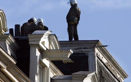 AMSTERDAM - Drie politieagenten gaan dinsdag via het dak een kraakpand aan de amsterdamse Weteringschans binnen. De politie houdt sinds dinsdagochtend vroeg in Amsterdam een ontruimingsronde van diverse kraakpanden. Rond 14.30 uur had ze in totaal zes per