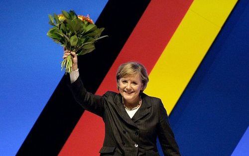 DRESDEN - De Duitse bondskanselier Angela Merkel en voorzitter van de Christendemocratische Unie (CDU) zwaait na haar herkiezing met een bos bloemen naar gedelegeerden. In totaal waren 1000 afgevaardigden bij elkaar voor de partijvoorzittersverkiezing. Fo