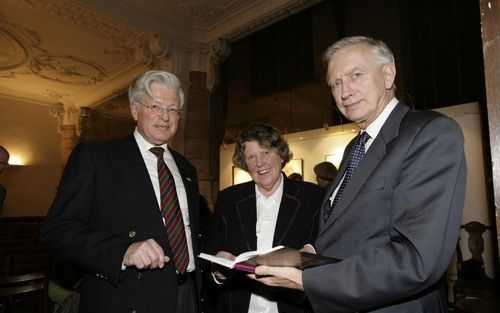 GOUDA – Ds. G. H. Abma jr. (l.) overhandigt in de St. Janskerk van Gouda de biografie van zijn vader, ds. H. G. Abma, aan oud-Kamervoorzitter dr. D. Dolman. De auteur, H. A. van Dolder de Wit, kijkt toe.