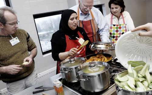 LELYSTAD – VVD raadslid Van Erk uit Lelystad (tweede van rechts) buigt zich over een pan met rundvlees. Samen met zijn collega’s Zweers (Leefbaar Lelystad) (l.) en Middelkoop (PvdA) (r.) bereidde hij donderdag Marokkaanse couscous. De politici volgden een