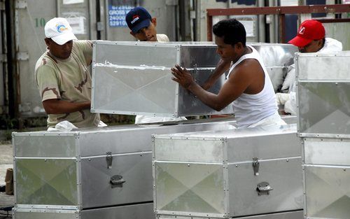 BAN MUANG – Thaise arbeiders droegen woensdag aluminiumkisten uit een mortuarium. De kisten bevatten de lichamen van slachtoffers van de tsunami van 26 december 2004. Het ging om 110 niet geïdentificeerde lichamen. Ze werden begraven op de begraafplaats b