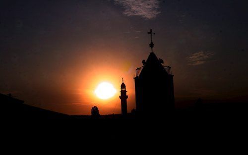 ZABABDA – Kerk en moskee in het dorpje Zababda op de Westelijke Jordaanoever, donderdag bij zonsondergang. Door het toenemende geweld in het Midden Oosten kiezen steeds meer christenen voor emigratie. Foto EPA