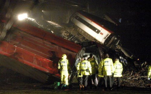 Reddingswerkers inspecteren de ontspoorde trein.