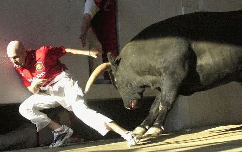 Een man wordt op de hielen gezeten door een woedende stier op het San FermÃ­n-festival in het Baskische Pamplona. - Foto EPA