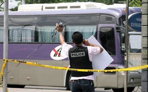 Een Fillipijnse politieman probeert contact met de gijzelnemers te krijgen. Twee gewapende mannen hebben woensdag in Manilla een schoolbus gegijzeld met 32 kinderen en twee leraren aan boord. Foto EPA