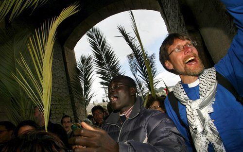 JERUZALEM – Christelijke pelgrims lopen door de Leeuwenpoort de Oude Stad van Jeruzalem binnen. Zingend en met palmtakken in de handen lopen de pelgrims de route die Jezus zou hebben gelopen tijdens Zijn intocht in Jeruzalem. Foto: EPA