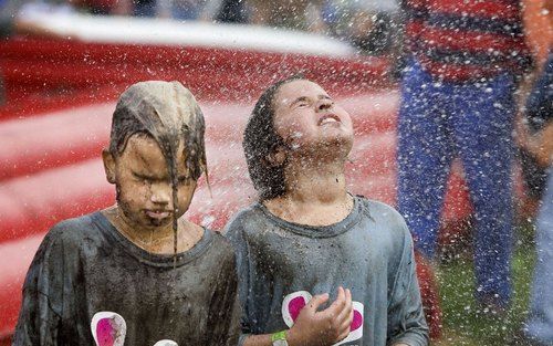 AMSTERDAM – Kinderen krijgen een wasbeurt na een modderig Nederlands Kampioenschap Buitenspelen in Amsterdam. Op het kampioenschap werden zes spellen voor buiten gespeeld die gebaseerd waren op een sport. In de leefdtijdscategorie van vijf tot en met tien