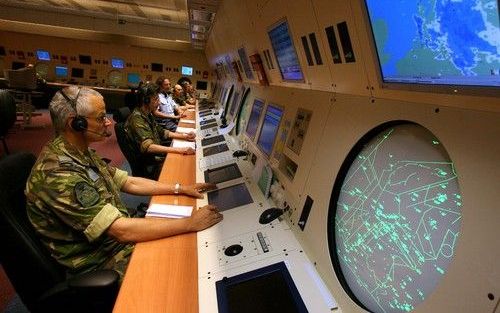 NIEUW MILLIGEN – Verkeersleiders in de bunker van de militaire luchtverkeersleiding in Nieuw-Milligen hebben achter grote panelen contact met de buitenwereld. Talrijke vliegtuigen bewegen zich als groene streepjes over een radarscherm rechtsonder), terwij