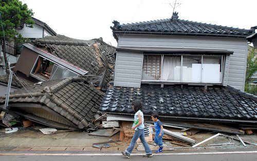 KASHIWAZAKI - Ineengestorte woningen in Kashiwazaki-Stad. Een dag na de aardbeving beginnen mensen terug te keren naar hun ruiïnes om hun belangrijkste bezittingen bijeen te sprokkelen. Foto EPA.