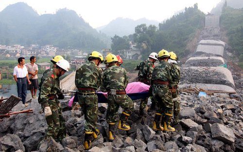 Reddingswerkers dragen overledenen weg na het instorten van een in aanbouw zijnde brug in Fenghuang, centraal China. Foto EPA