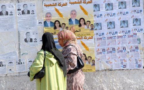 CASABLANCA – Twee vrouwen passeren in de Marokkaanse stad Casablanca een muur vol verkiezingsposters. Vrijdag kiest het Noord Afrikaanse land een nieuw parlement. Foto EPA