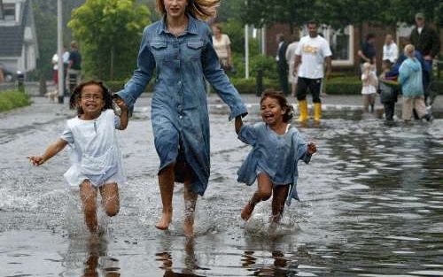 RIJSSEN - Kinderen rennen door het water na een wolkbreuk in het Overijsselse Rijssen. Het centrum van Rijssen kwam zondagochtend blank te staan na een wolkbreuk. In sommige delen van Rijssen stond het water 75 centimeter hoog. - Foto ANP