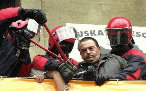 BILBAO - Gemaskerde agenten van de regionale Baskische politie ontruimen het kantoor van de radicale partij Herri Batasuna in Bilbao en houden Carmelo Landa in bedwang. Landa is lid van het nationale comitÃ© van de partij. - Foto EPA