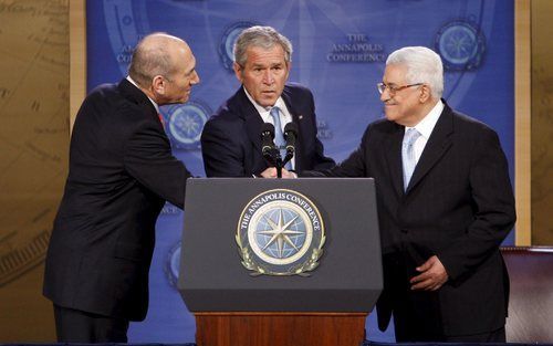 ANNAPOLIS – De Israëlische premier Ehud Olmert (l.) schudt de hand van de Palestijnse premier Mahmud Abbas (r.) terwijl de Amerikaanse president George Bush toekijkt. De verschillende partijen kwamen dinsdag overeen dat het vredesoverleg tussen Israël en 