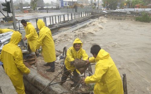 ATHENE - Inwoners van Athene proberen met zandzakken het centrum te beschermen tegen het water uit de Kiffisos. De Griekse hoofdstad werd donderdag getroffen door noodweer, waarop het openbare leven stil kwam te liggen. - Foto EPA