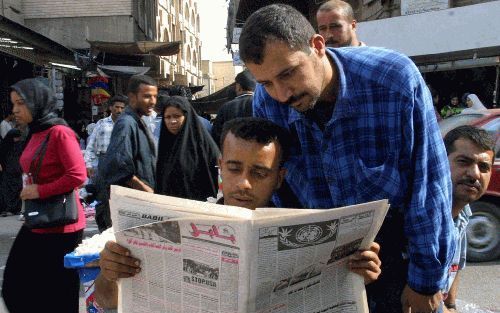 BAGDAD - Iraakse mannen volgen op straat in Bagdad de laatste ontwikkelingen rond de VN-resolutie over wapeninspecties. Het Iraakse parlement adviseerde Saddam Hussein maandag de uitspraak van de Veiligheidsraad naast zich neer te leggen. - Foto EPA