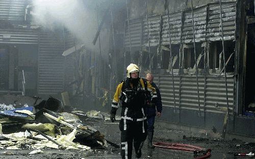 SCHIPHOL - Een brandweerman loopt langs het uitgebrande cellencomplex op Schiphol-Oost. Het gebouw zou over twee weken worden opgeleverd. - Foto ANP