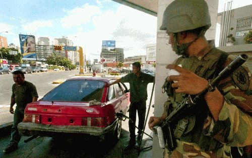 CARACAS - Een soldaat van het Venezolaanse leger staat op wacht bij een tankstation in Caracas. De olieprijzen zijn sterk gestegen als gevolg van de stakingsacties, die de olie-industrie in het land hebben stilgelegd. - Foto EPA