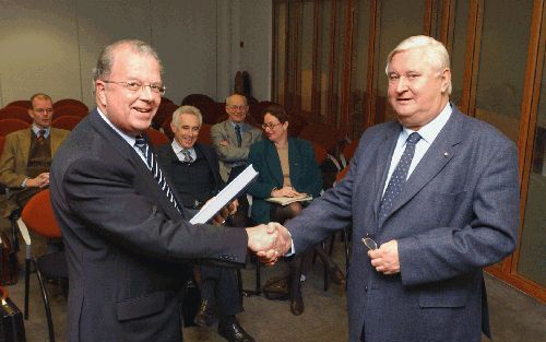 UTRECHT - De preses van de hervormde synode, ds. A. W. van der Plas (l.), neemt het boek ”Delen of helen” in ontvangst van de auteur, dr. ir. J. van der Graaf. Het boek behandelt de wederwaardigheden in en met de Gereformeerde Bond tussen 1951 en 1981. De