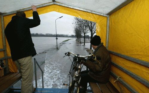 MAASTRICHT - Twee Limburgers kijken vanuit een vrachtwagen naar het water op een ondergelopen weg. Tussen Maastricht en de dorpen Itteren en Borgharen is een pendeldienst ingesteld. - Foto ANP