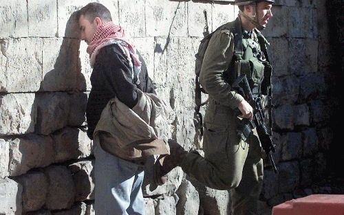 HEBRON - Een IsraÃ«lische militair bewaakt een gearresteerde Palestijn in Hebron. Na ruim twee jaar intifada dringt ook bij de Palestijnen langzaam maar zeker het besef door dat ze deze minioorlog met IsraÃ«l hebben verloren. - Foto EPA