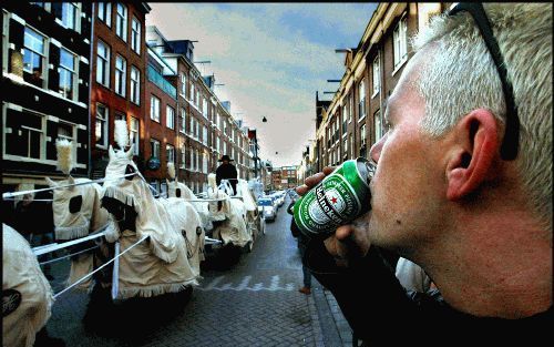 AMSTERDAM - Een toeschouwer drinkt een blikje bier, terwijl de stoet met het lichaam van de crimineel Van Hout in de Willemstraat in de Jordaan passeert. De witte koets werd voortgetrokken door acht met witte sierkleden bedekte Friese paarden, gevolgd doo